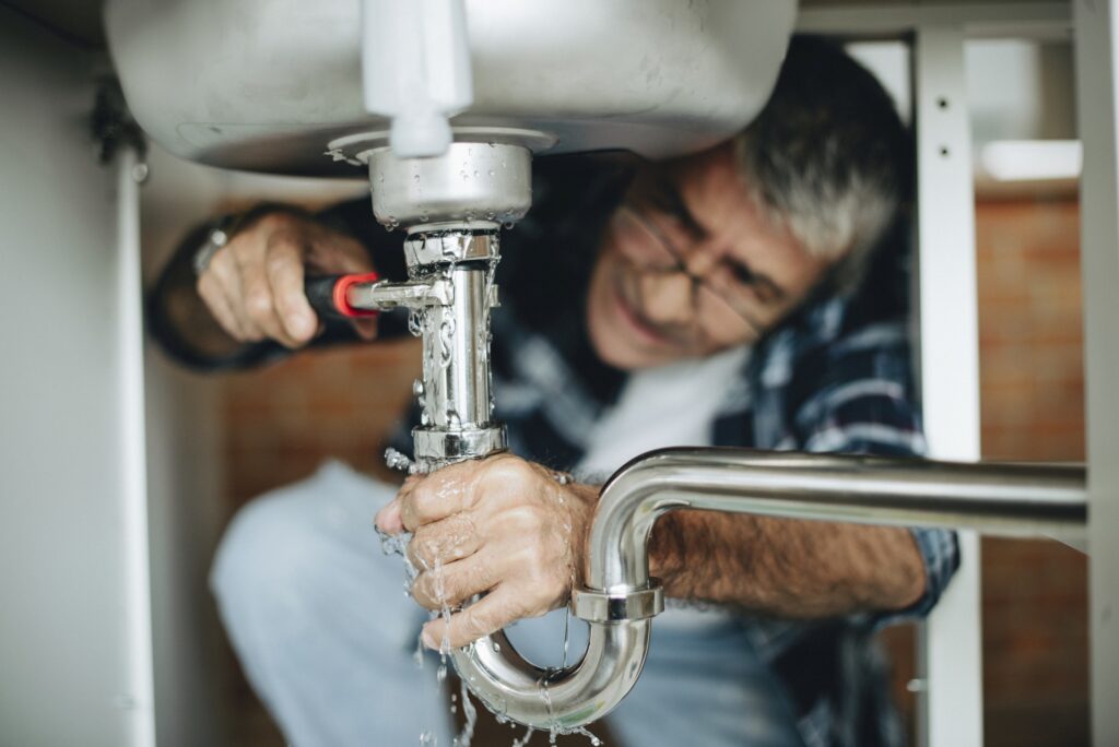Plumber working on the pipework beneath a sink