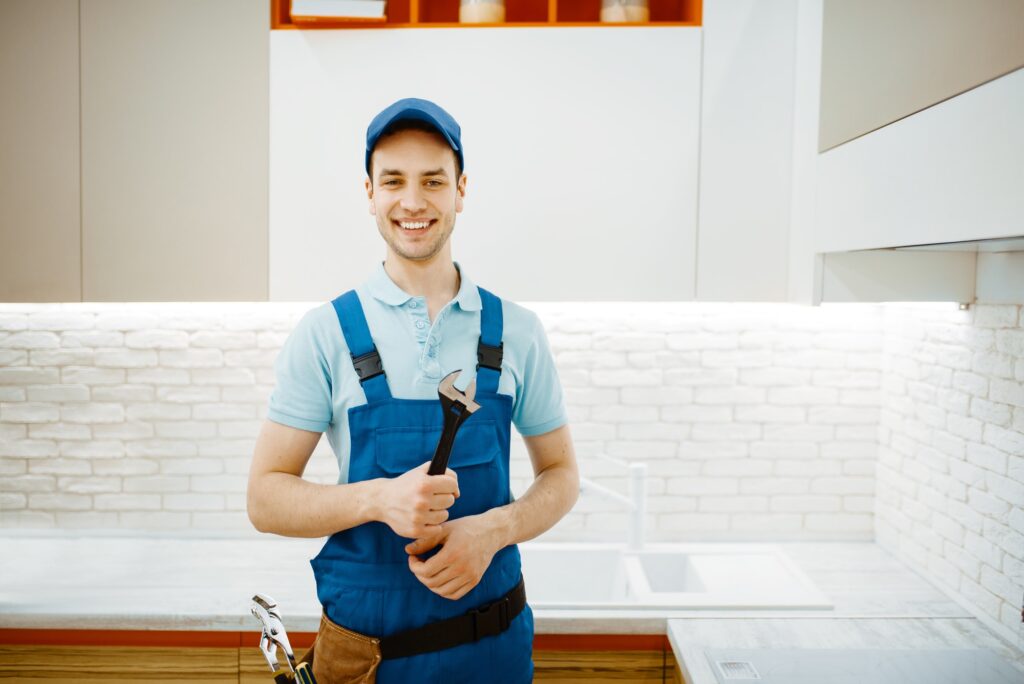 Plumber in overalls standing in a kitchen