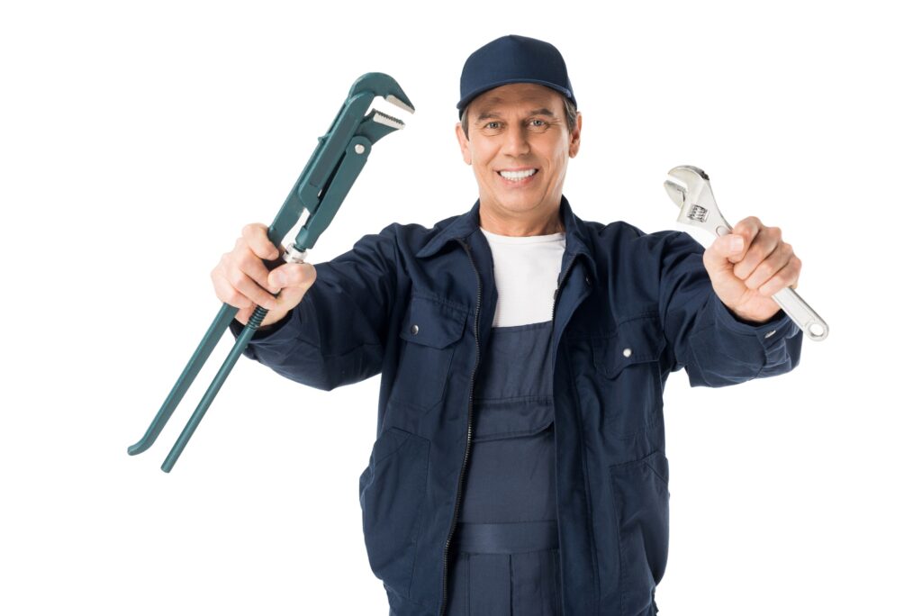 Plumber in overalls holding two pipe wrenches