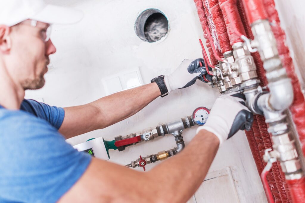 Plumber fitting pipework and valves on a wall